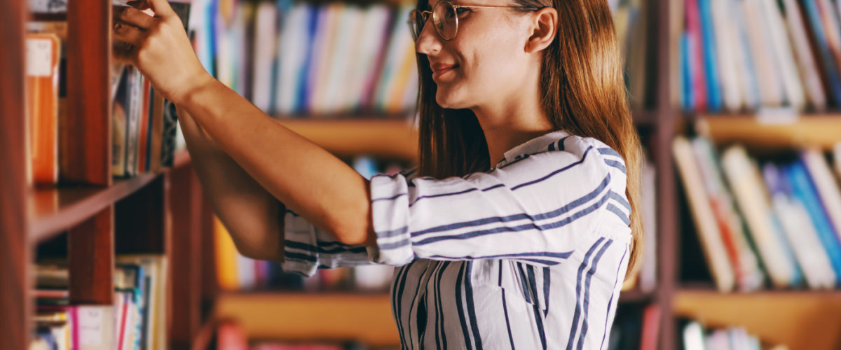 Femme prennant un livre d'une bibliothèque